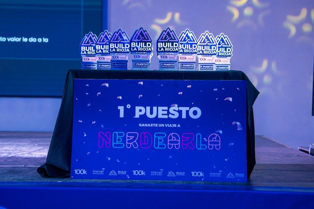 Los trofeos de #BuildLaRioja junto al cartel del primer puesto: un viaje a Nerdearla