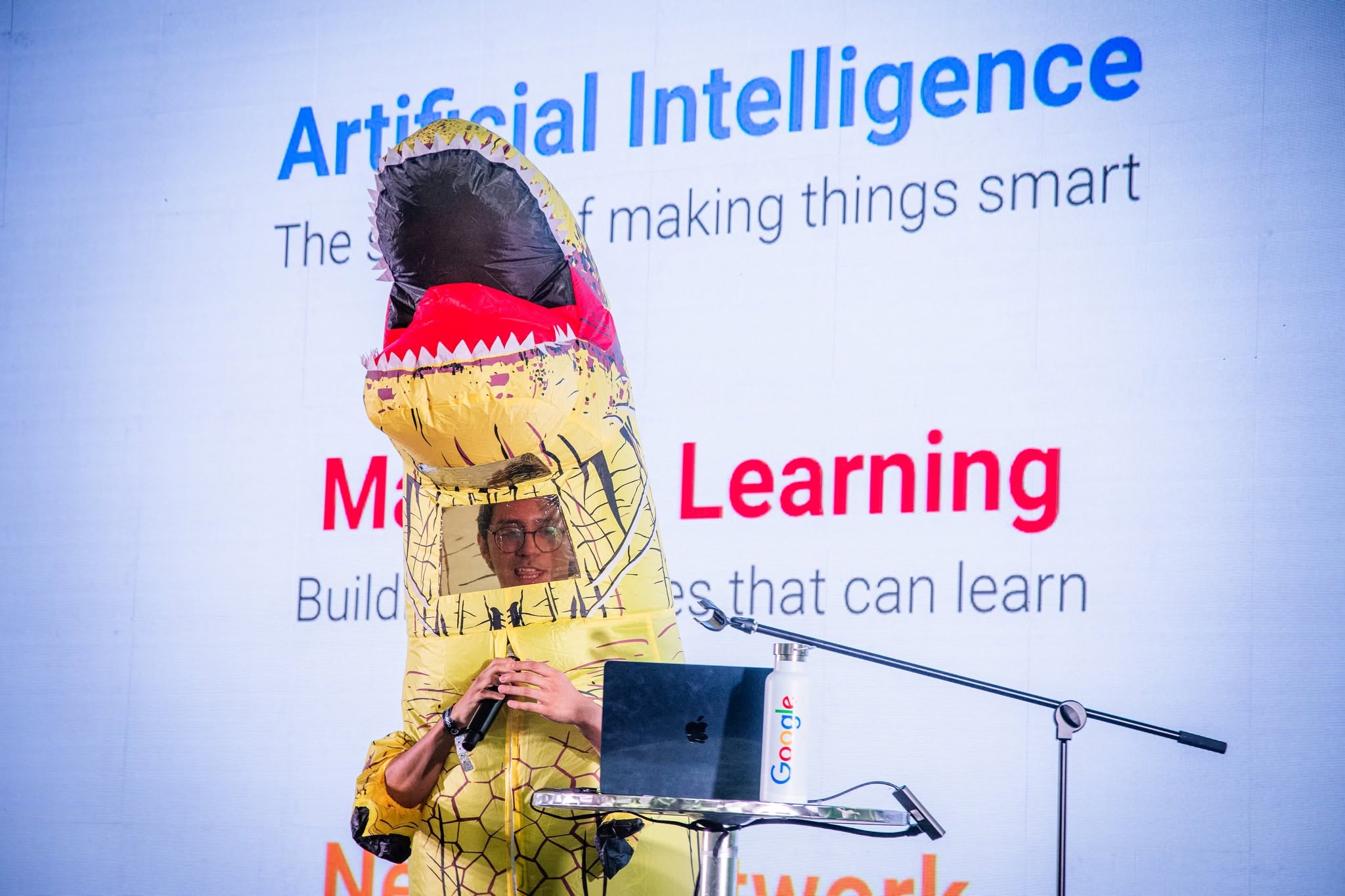A speaker in a dinosaur costume gives a talk about artificial intelligence
